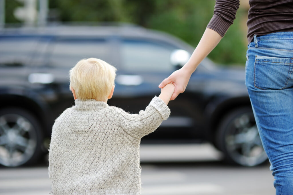 Mother and toddler son crossing the street on the crosswalk close up