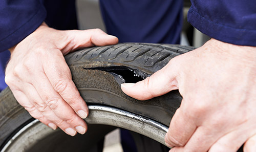 Close Up Of Mechanic Examining Damaged Car Tire