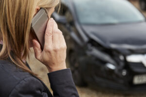 a woman on the phone talking to her insurance company after a car accident.