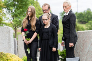Family on cemetery or graveyard mourning deceased relative
