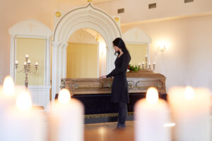 burial, people and mourning concept - sad woman with coffin at funeral in orthodox church