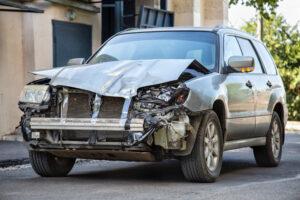 Crashed car in car accident. Broken vehicle after fatal disaster. Road collision damage. Gray car get damaged by accident. Damaged automobile after collision