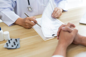 Visiting a doctor concept A doctor rating health condition of his patient while listening to his patient’s symptom