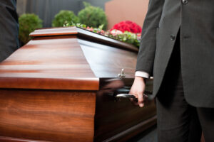 Religion, death and dolor - coffin bearer carrying casket at funeral to cemetery
